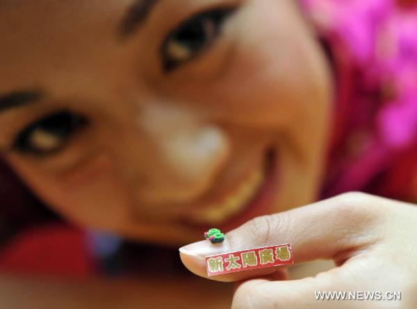 A model demonstrates the pair of world&apos;s smallest shoes by Guinness World Record in Hong Kong, south China, Jan. 20, 2011. Thirty-five pairs of mini shoes were displayed in Hong Kong Thursday including the world&apos;s smallest pair that measured 3.8 millimeters long, 1.8 millimeters wide and 2.2 millimeters high. [Xinhua] 