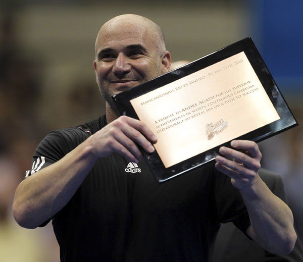 Andre Agassi of the U.S. shows a plaque he received after an exhibition tennis match against Brazil's Gustavo Kuerten in Rio de Janeiro December 11, 2010. (Xinhua/Reuters file Photo)