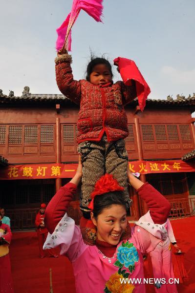 A member of a flower-drum troupe teaches a girl to dance during a rehearsal at the Fengzuizi village of Bengbu, east China's Anhui Province, Jan. 19, 2011, to greet the traditional Spring Festival, which falls on Feb. 3 this year. Flower-drum dance, a folk dance featuring lantern performances and percussion instruments integrated in harmony, is popular along the Huaihe river areas of China. Fengzuizi village of Bengbu is cited as a famous village for flower-drum dance. 