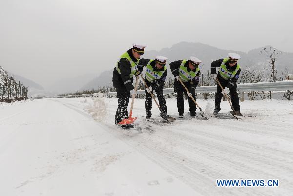 Traffic police clear snow on a highway in Chongqing municipality, southwest China, Jan. 20, 2011. Snow in parts of the city has accumulated up to 15 centimeters high after witnessing four days of snow in a row. 