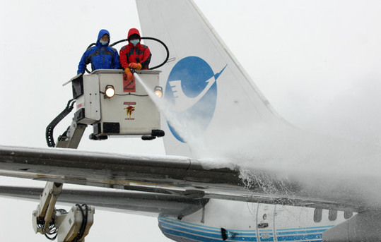 Workers remove snow from an aircraft at Hangzhou Xiaoshan International Airport on Thursday. [Xinhua]
