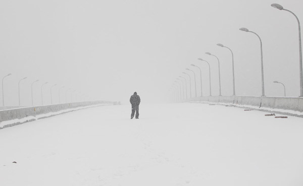 A pedestrian walks during snowfall in Shanghai Jan 20, 2011. China&apos;s National Meteorological Center and the Shanghai Meteorological Bureau have issued a warning for heavy snowfall in Shanghai for Thursday and Friday.