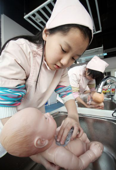 Pupils clean doll babies in simulation of nurses during an activity of the winter camp, in Tianjin, Jan 22, 2011. Students in Tianjin are fond of spending their winter vacation in the camp to experience grown-up lives in simulation of different social roles. [Photo/Xinhua] 