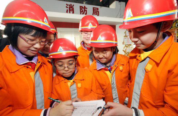 Pupils from the second primary school affiliated to the Tianjin Normal University work in simulation of fire fighters during an activity of the winter camp, in Tianjin, north China, Jan 22, 2011. Students in Tianjin are fond of spending their winter vacation in the camp to experience grown-up lives in simulation of different social roles. [Photo/Xinhua]