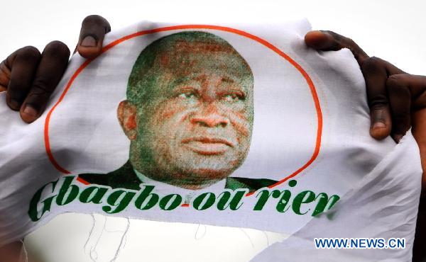 A supporter of Cote d&apos;Ivoire&apos;s incumbent Laurent Gbagbo holds Gbagbo&apos;s portrait during a gathering at the Champroux stadium in Abidjan, Cote d&apos;Ivoire, Jan. 23, 2011. [Xinhua]