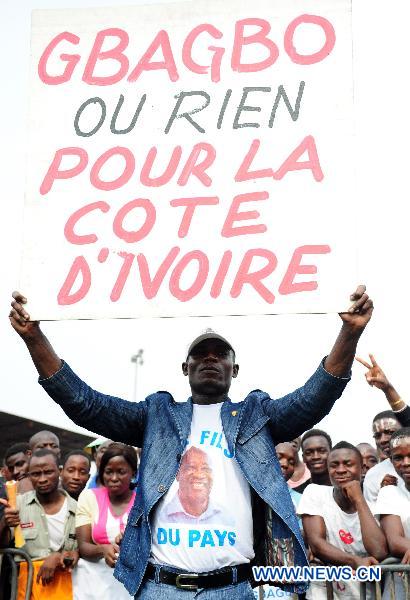 A supporter of Cote d&apos;Ivoire&apos;s incumbent Laurent Gbagbo holds a placard during a gathering at the Champroux stadium in Abidjan, Cote d&apos;Ivoire, Jan. 23, 2011. [Xinhua]