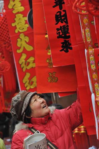 A woman buys New Year decorations at a market in Hefei, capital of East China&apos;s Anhui province, Jan 23, 2010. [Photo/Xinhua] 