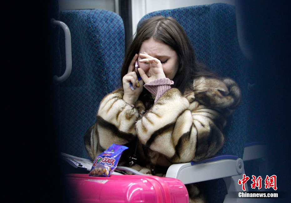 A woman cries while talking on the phone to an acquaintance who is at Domodedovo airport, as she travels by train to the airport from Moscow January 24, 2011. [Photo/Chinanews.com]