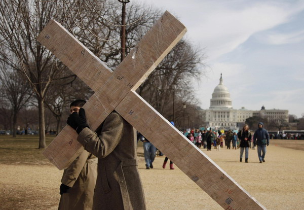 A pro-life protester carries a crucifix in front of the US Capitol Building on the Washington Mall during the annual March for Life, Jan 24, 2011. [China Daily/Agencies]