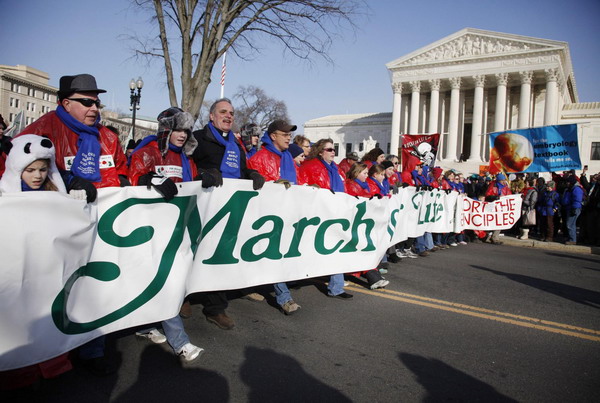 Pro-life protesters carry a giant banner as they march past the US Supreme Court during their annual March for Life in Washington Jan 24, 2011. [China Daily/Agencies]