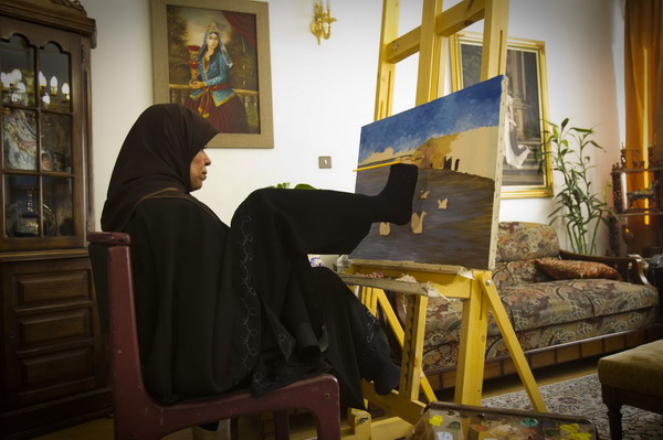 Zohre Etezadolsaltaneh, 49, works on a painting using her foot at her home in Tehran Jan 24, 2011. Etezadolsaltaneh, a retired special education teacher, was born with no arms but lives the life of an independent woman who has been doing cooking, painting, weaving kilims and taking care for her mother who is a cancer patient. She gets $600 per month as pension from the government and lives by the mantra &apos;To want is to succeed.&apos; [China Daily/Agencies]