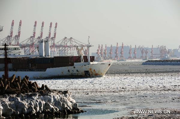 The freighter &apos;Lilac&apos; slides from the sea ice surrounded Yingkou port, northeast China&apos;s Liaoning Province, Jan. 24, 2011. The transportation and production at the sea of Liaoning Province are affected by sea ice due to freezing weather. [Xinhua] 