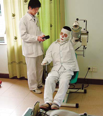 A patient suffering from facial burns receives treatment from an experienced medic at the rehab center in Guangzhou. 