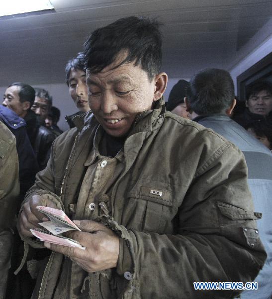 A migrant worker smiles as counting his salary released by a marine engineering company in Qinhuangdao, north China&apos;s Hebei Province, Jan. 24, 2010. The company released wages of January ahead of schedule for 340 migrant workers Monday, before they going back home for Chinese Spring Festival. [Xinhua]
