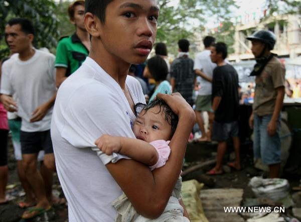 A resident protects his infant sibling as they evacuate from rocks and bottles during the demolition of shanties in San Juan City, north of Manila, Jan. 25, 2011. Some 40 people were injuried during the violent demolition that will affect more than 1,000 families in the area. [Xinhua]