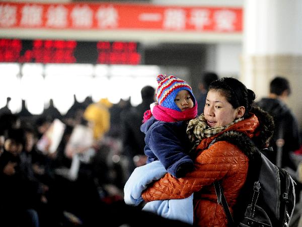 A woman holding her child waits for getting on a train at the Shenyang North Railway Station, in Shenyang, capital of northeast China&apos;s Liaoning Province, Jan. 25, 2011. According to an estimate based on the sales of train tickets, the station will witness a travel peak from Jan. 31 to Feb. 1, as the eve of the Chinese Spring Festival falls on Feb. 3 this year, which by tradition Chinese people should spend at home with family memebers. [Xinhua] 