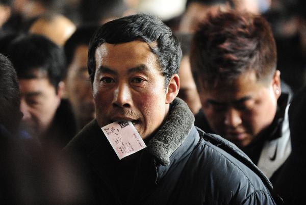 Passengers line up to get on trains at the Shenyang North Railway Station, in Shenyang, capital of northeast China&apos;s Liaoning Province, Jan. 25, 2011. According to an estimate based on the sales of train tickets, the station will witness a travel peak from Jan. 31 to Feb. 1, as the eve of the Chinese Spring Festival falls on Feb. 3 this year, which by tradition Chinese people should spend at home with family memebers. [Xinhua] 