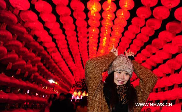 A woman poses for photo under a corridor decorated with red lanterns during the 17th Zigong International Dinosaur Lantern Festival in Zigong, southwest China's Sichuan Province, Jan. 24, 2011. The lantern festival, which kicked off on Monday, will last for 43 days to celebrate the Chinese Spring Festival which falls on Feb. 3 this year.