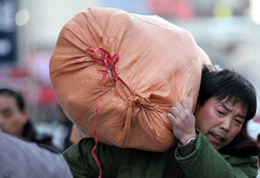 A passenger carries luggage at the Beijing West Railway Station, Jan 26, 2011. January 19 marked the beginning of the annual Spring Festival travel rush, with an expected 2.56 billion passenger trips in the coming 40 days. [Photo/Xinhua]
