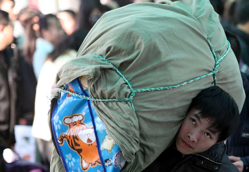 A passenger carries luggage at the Beijing West Railway Station, Jan 26, 2011. January 19 marked the beginning of the annual Spring Festival travel rush, with an expected 2.56 billion passenger trips in the coming 40 days. [Photo/Xinhua]