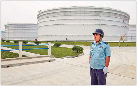 An armed police officer stands guard near large oil tanks at Zhenghai National Oil Reserve Base in Ningbo, Zhejiang province. China started to build oil reserve bases as early as 2003 to offset supply risks and reduce the impact of fluctuating energy prices.[China Daily]