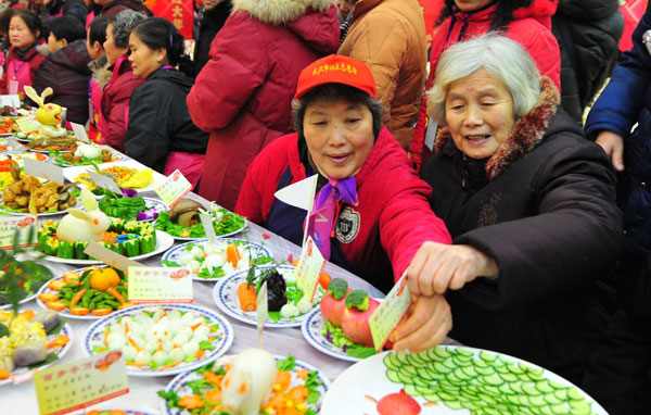 The 78-year-old resident Cao Manrong (1st R) tastes dishes during a grand feast held at the Baibuting Community in Wuhan, capital of Central China&apos;s Hubei province, Jan 27, 2011. [Photo/Xinhua]