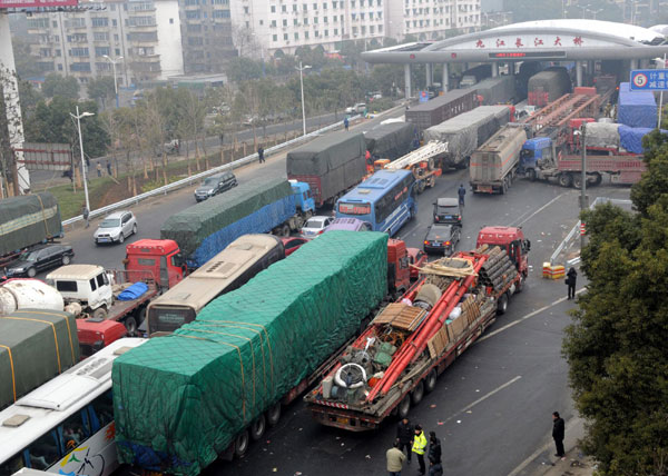 Cars wait in line to pass a toll station of the Jiujiang Yangtze River Bridge in Jiujiang, Jan 27, 2011. [Photo/Xinhua]