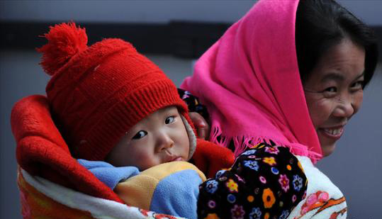 A woman carrying a baby waits for a train in Guiyang, Southwest China's Guizhou province, Jan 27, 2011. [Photo/Asianewsphoto]