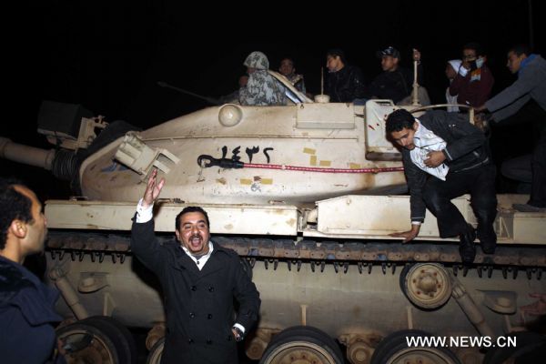 Demonstrators climb up to armed vehicles after clashes calmed down at Square Tahrir in Cairo, capital of Egypt, early on Jan. 29, 2011. Dozens of tanks entered the Square, while protestors welcomed the army and waved to the soldiers standing on tanks. [Xinhua] 