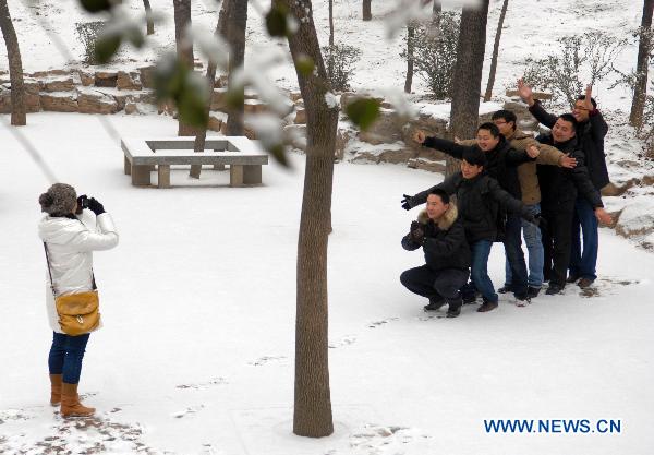 A woman takes photos for her friends in snow in the Quancheng Park in Jinan, capital of east China's Shandong Province, Jan. 28, 2011. 