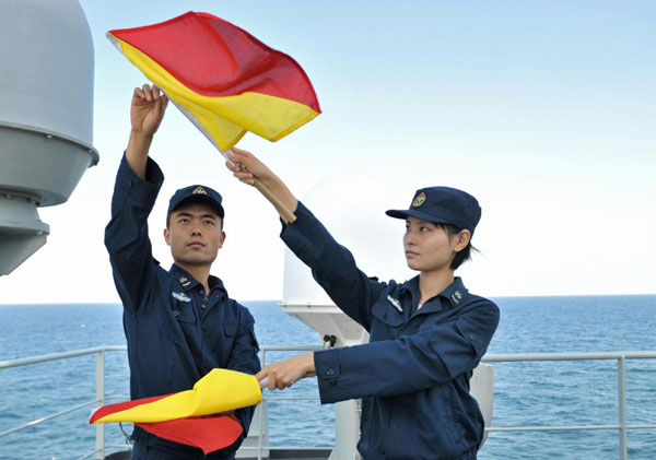 Photo taken on Jan. 12, 2011 shows female soldier Zhang Yan (R) learning flag signals on the Chinese supplying ship &apos;Qiandaohu&apos;. [Photo/Xinhua]