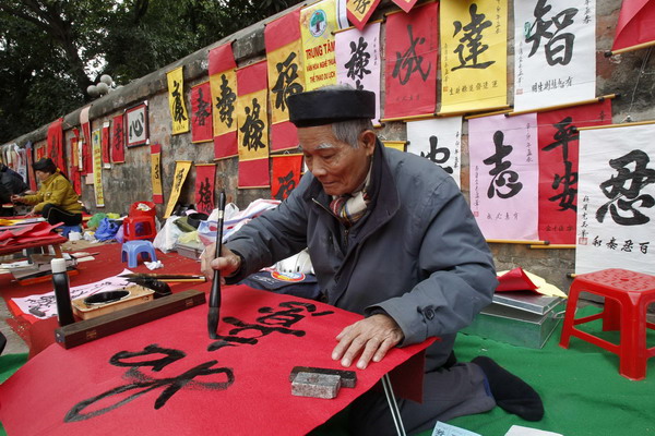 A calligrapher paints on a street in Hanoi Jan 28, 2011. [China Daily/Agencies]