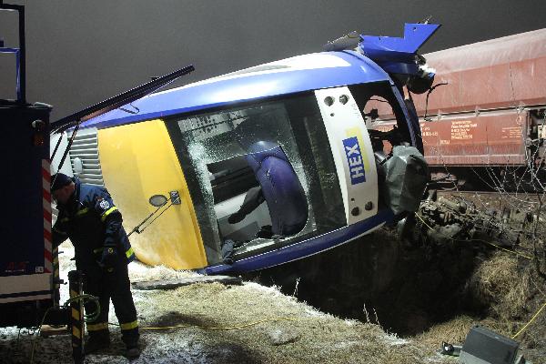 Rescue workers stands beside a overturned train after a train crash in Hordorf near Oschersleben, eastern Germany, Jan 30, 2011. A passenger and a freight train collided with each other late Saturday in eastern Germany, leaving at least 10 people dead and about 20 seriously injured, police said. [Xinhua/AFP]