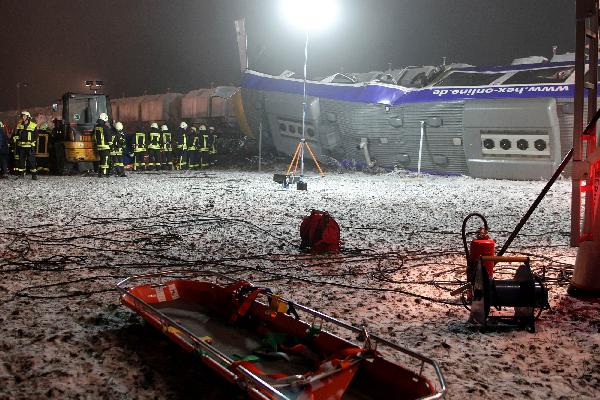 Rescue workers stands beside a overturned train after a train crash in Hordorf near Oschersleben, eastern Germany, Jan 30, 2011.[Xinhua/AFP]