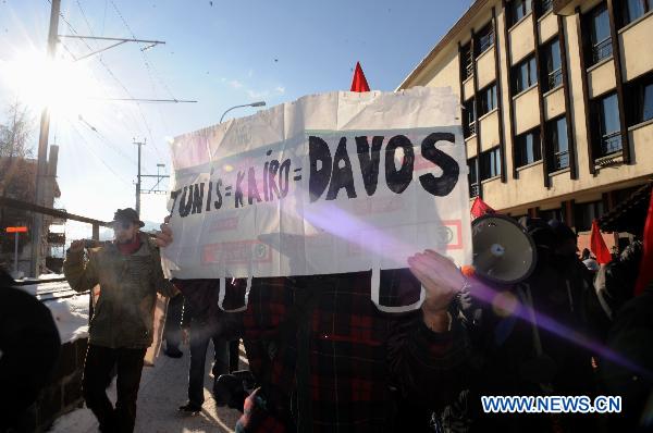 A protester holds a slogan during a demonstration against the World Economic Forum in Davos, Switzerland, on Jan. 29, 2011. [Xinhua]