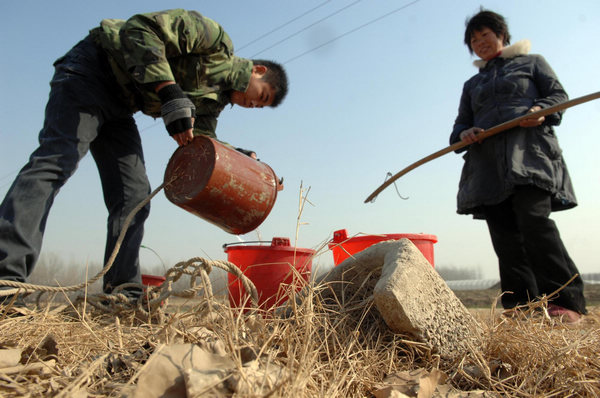 A farmer (L) fetches water from an irrigation well in Heze, East China&apos;s Shandong province on Jan 24.