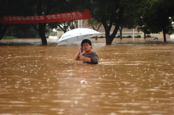 A file photo taken on June 20, 2010, shows a resident walking along a flooded road in Yujiang county in East China&apos;s Jiangxi province. [Xinhua]