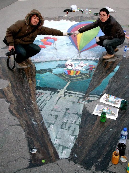 Two painters pose with their nearing completion 3D street painting at Xuanwu Lake Park on January 30, 2011 in Nanjing, Jiangsu Province of China. [Photo/CFP]