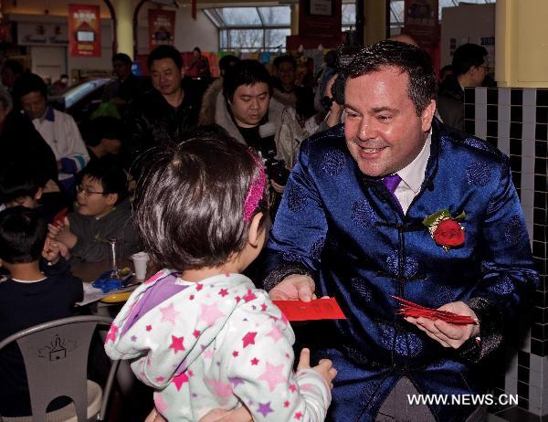 Canadian Minister of Citizenship, Immigration and Multiculturalism Jason Kenney (R) gives gift money to a girl during a New Year reception at an overseas Chinese community in Greater Toronto Area, Canada, on Jan. 29, 2011.