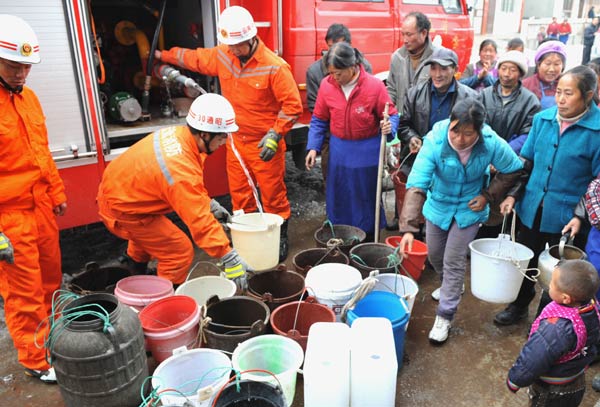 Villagers wait to get their buckets filled with water piped from a fire engine sent out by the local fire prevention brigade in Yiliang county of Zhaotong, Southwest China&apos;s Yunnan province, Jan 24, 2011. Since the start of this winter, freezing weather has disrupted the drinking water supply in the area. [Photo/Xinhua] 