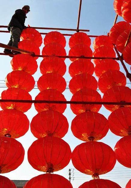 A worker adjusts red lantern decorations for the Spring Festival in a community in Zouping county of Binzhou, East China&apos;s Shandong province, Jan 24, 2011. [Photo/Xinhua]