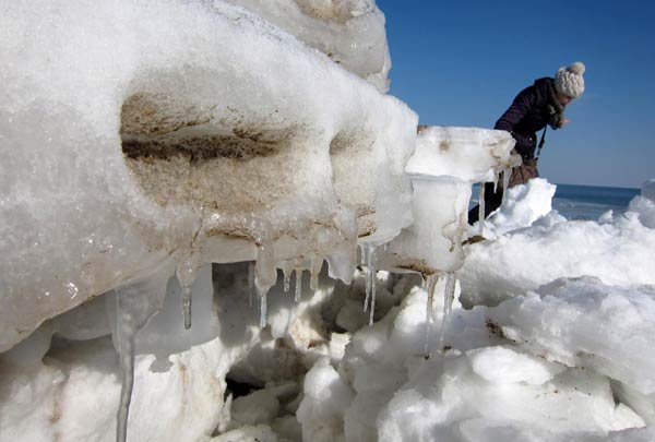 A resident in Huludao city, Northeast China&apos;s Liaoning province, looks at the ice pile at a local beach, Jan 29, 2011. Chilly temperatures caused thousands of hectares of sea surface to freeze this winter. [Photo/Xinhua]