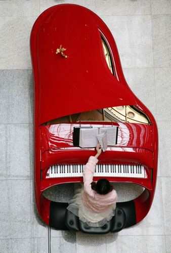 A girl plays piano at Deji Square in Nanjing, East China&apos;s Jiangsu province, Jan 31, 2011. The piano, of the same painting technique of a Ferrari, is worth two million yuan ($302,984). It is dubbed a piano version of Rolls-Royce. [Photo/Xinhua]