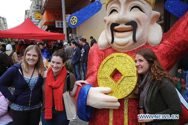 Girls pose with a statue of the god of wealth on a fair celebrating the Chinese Lunar New Year held in the Chinatown in San Francisco, the United States, Jan. 30, 2011. 