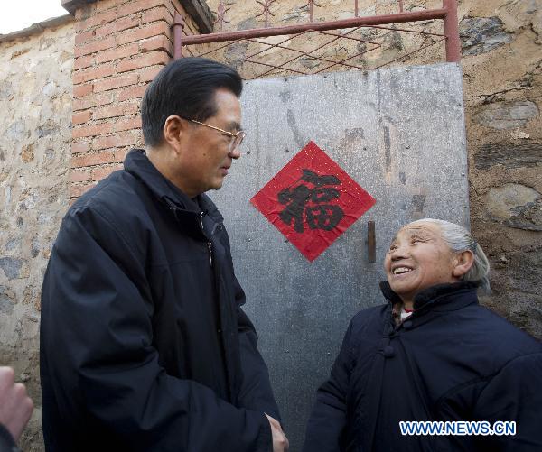 Chinese President Hu Jintao (L) talks with Yan Deshu, an aged member of Communist Party of China, next to the gate of Yan's home in Shijiatong Village, Xishanbei Township of Baoding City, north China's Hebei Province, Feb. 2, 2011. Hu pasted the Chinese character 'Fu', meaning fortune and happiness, for Yan's home. Hu made a tour in Baoding from Feb. 1 to 2 to welcome the Spring Festival, or China's Lunar New Year, with local officials and residents.