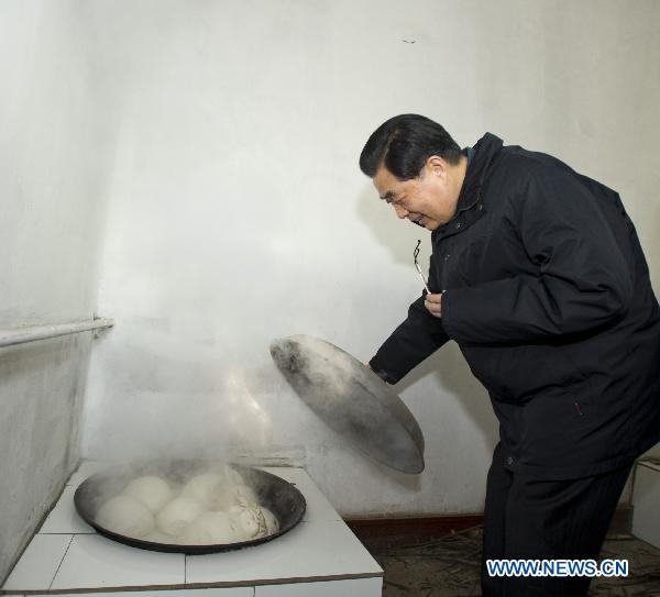 Chinese President Hu Jintao feels pleasant while looking at the steam bread prepared for festival meals in the home of Yan Deshu, an aged member of Communist Party of China, in Shijiatong Village, Xishanbei Township of Baoding City, north China's Hebei Province, Feb. 2, 2011. Hu made a tour in Baoding from Feb. 1 to 2 to welcome the Spring Festival, or China's Lunar New Year, with local officials and residents.