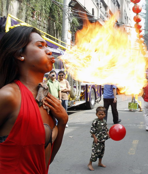 A performer spits fire on the eve of Chinese New Year along a main street of Chinatown in Binondo, metro Manila February 2, 2011.