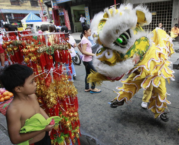 A Filipino boy watches lion dancers as they perform for a fee in front of a shop for the upcoming Chinese New Year along a busy street in Manila's Chinatown February 1, 2011.