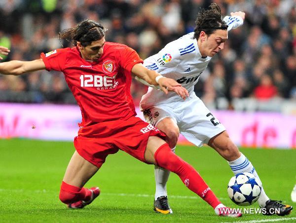 Real Madrid's Mesut Ozil (R) vies for the ball during the Spanish King's Cup semifinal second-leg football match between Real Madrid and Sevilla at the Santiago Bernabeu stadium in Madrid, capital of Spain, Feb. 2, 2011. Real Madrid won 2-0.