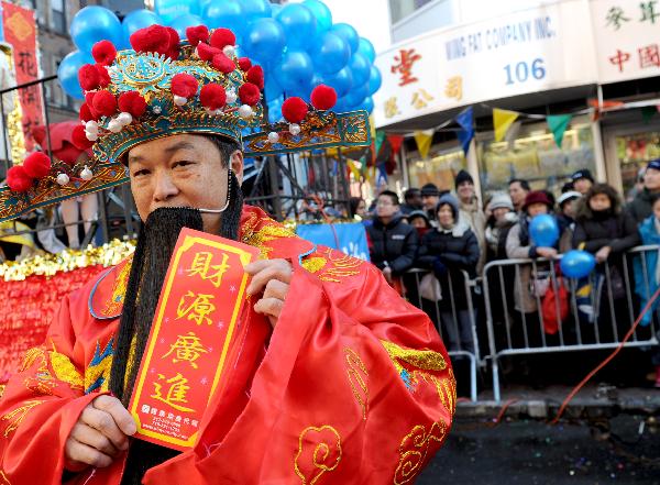 A man dressed himself as the God of Fortune poses for photos during the Chinese New Year parade to celebrate the Chinese Lunar New Year, the Year of the Rabbit, in Chinatown of New York, the United States, Feb. 6, 2011. 